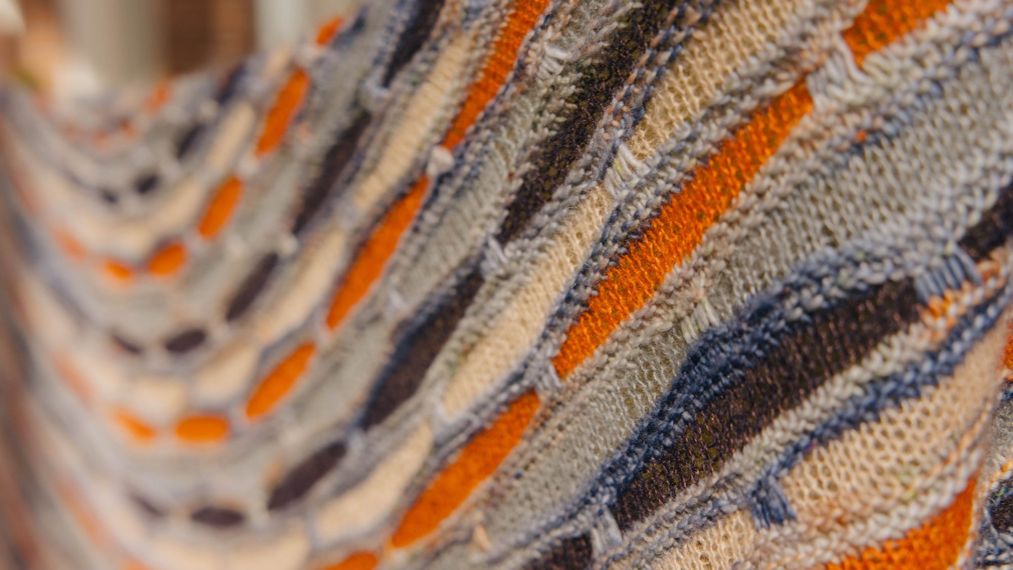Close up of the Painting Bricks Shawl in custom Shangdrok Single Merino colorway. This knit shawl is designed by Stephen West and knit in blue and oranges shades.